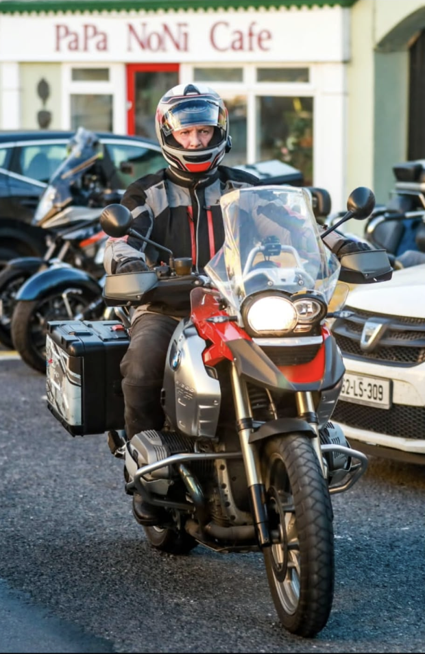 Mick Nolan riding his red BMW adventure motorcycle in full protective gear.